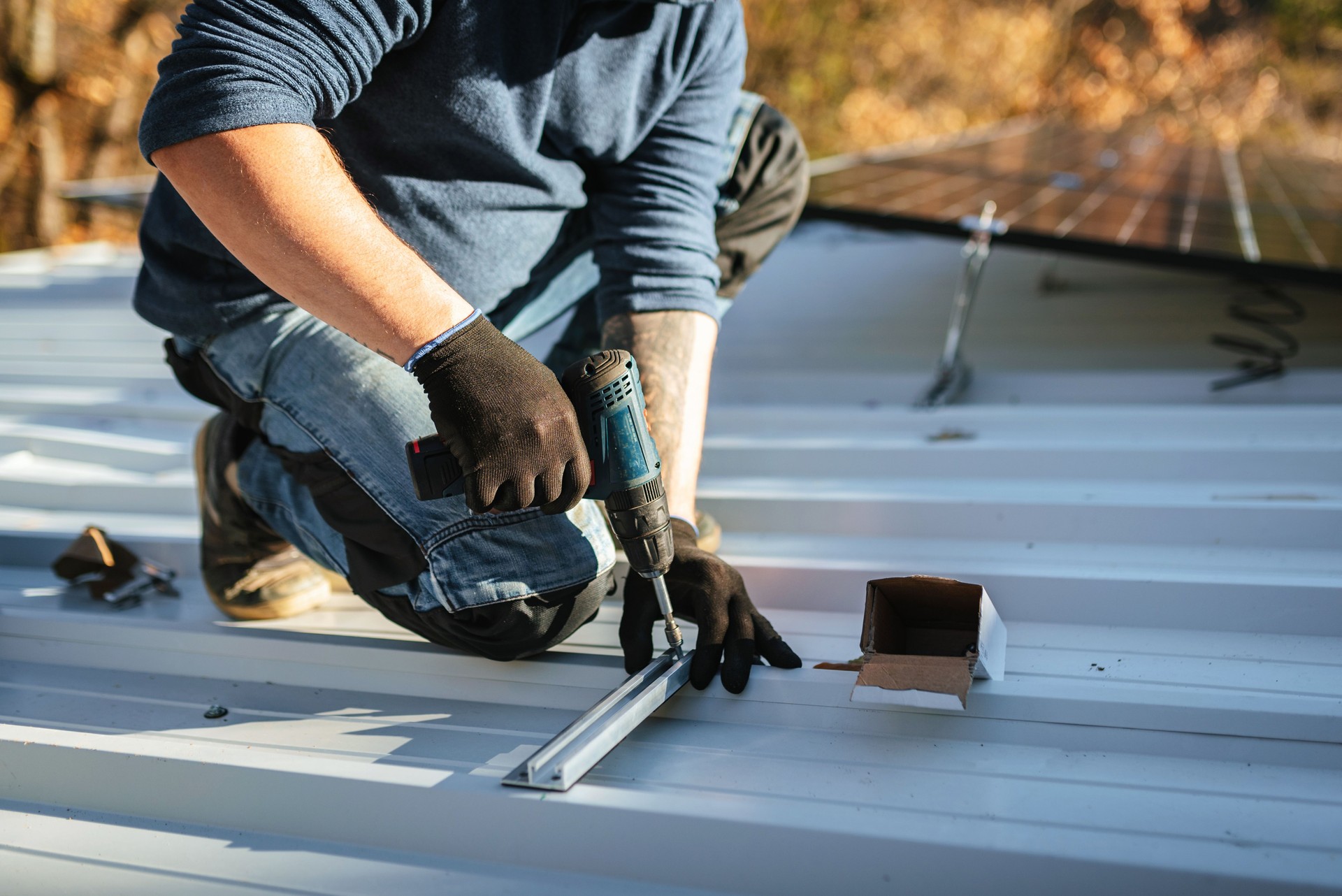 Worker using drill to fix solar panels