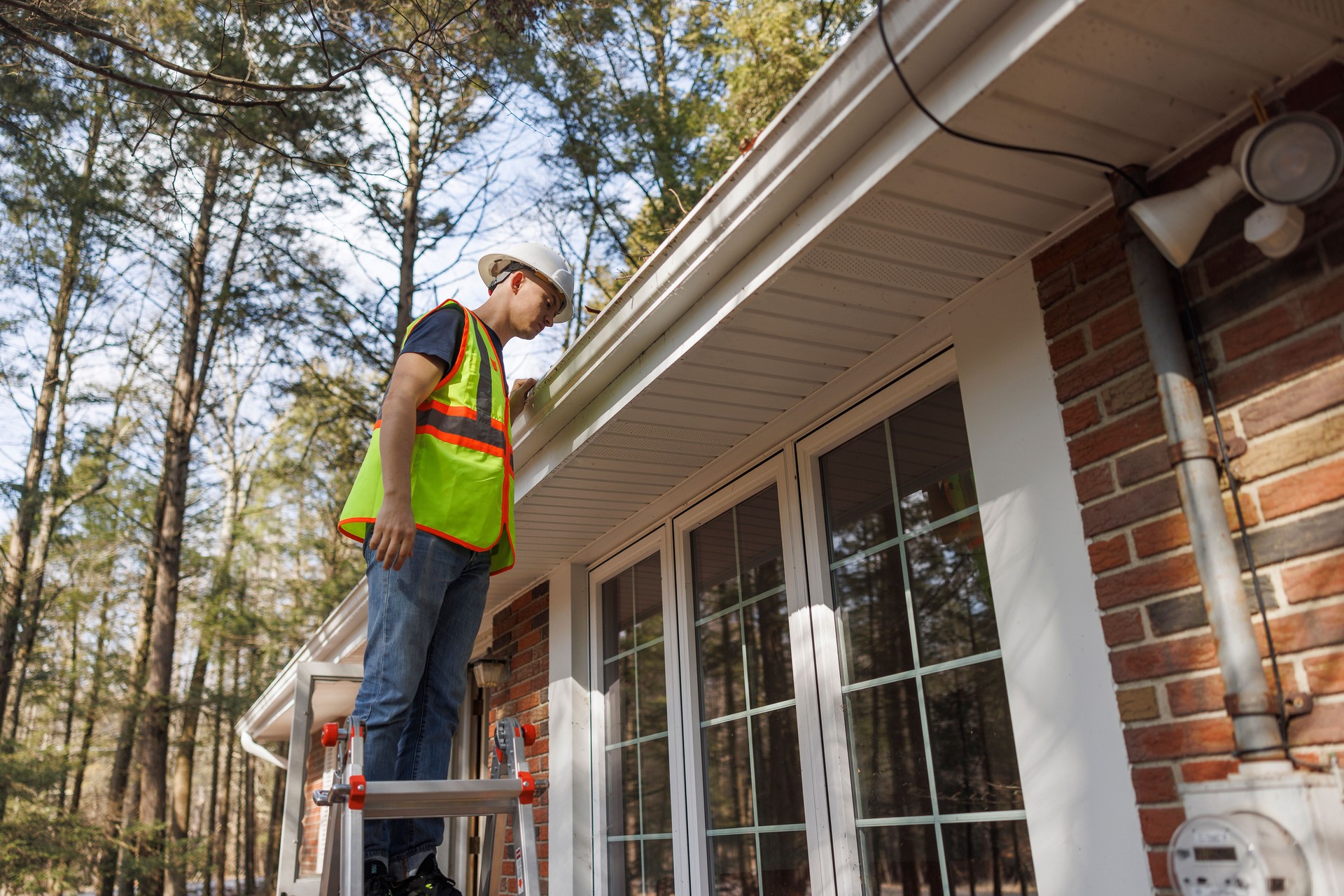 Blue collar worker  is inspecting the roof of the house for gutter cleaning. Focus on the foreground with defocused background.